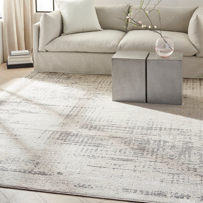 Neutral living room with beige sofa, textured cream rug, concrete block side tables, and vase with blossom branches.