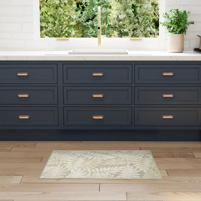 Dark navy kitchen drawers with brass handles, white countertop and gold faucet; mint leaf-pattern rug on wood floor.