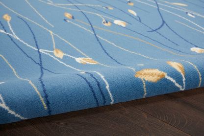 Blue plush area rug with abstract white and gold lines on dark wood floor