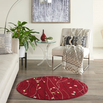 Round red rug with cream and gold vine pattern in a modern beige living room with plants, glass table and throws.