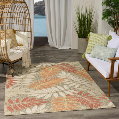 Modern woven rug with beige, peach and sage leaf pattern; rattan chair, white curtains, and leafy plants.