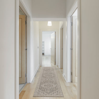 Bright hallway with white walls, light wood doors, a beige patterned runner rug, and a pendant ceiling light.