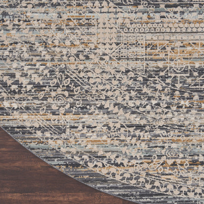 Round distressed oriental rug in blue, gray, cream & tan with vintage floral motifs on dark wood floor.