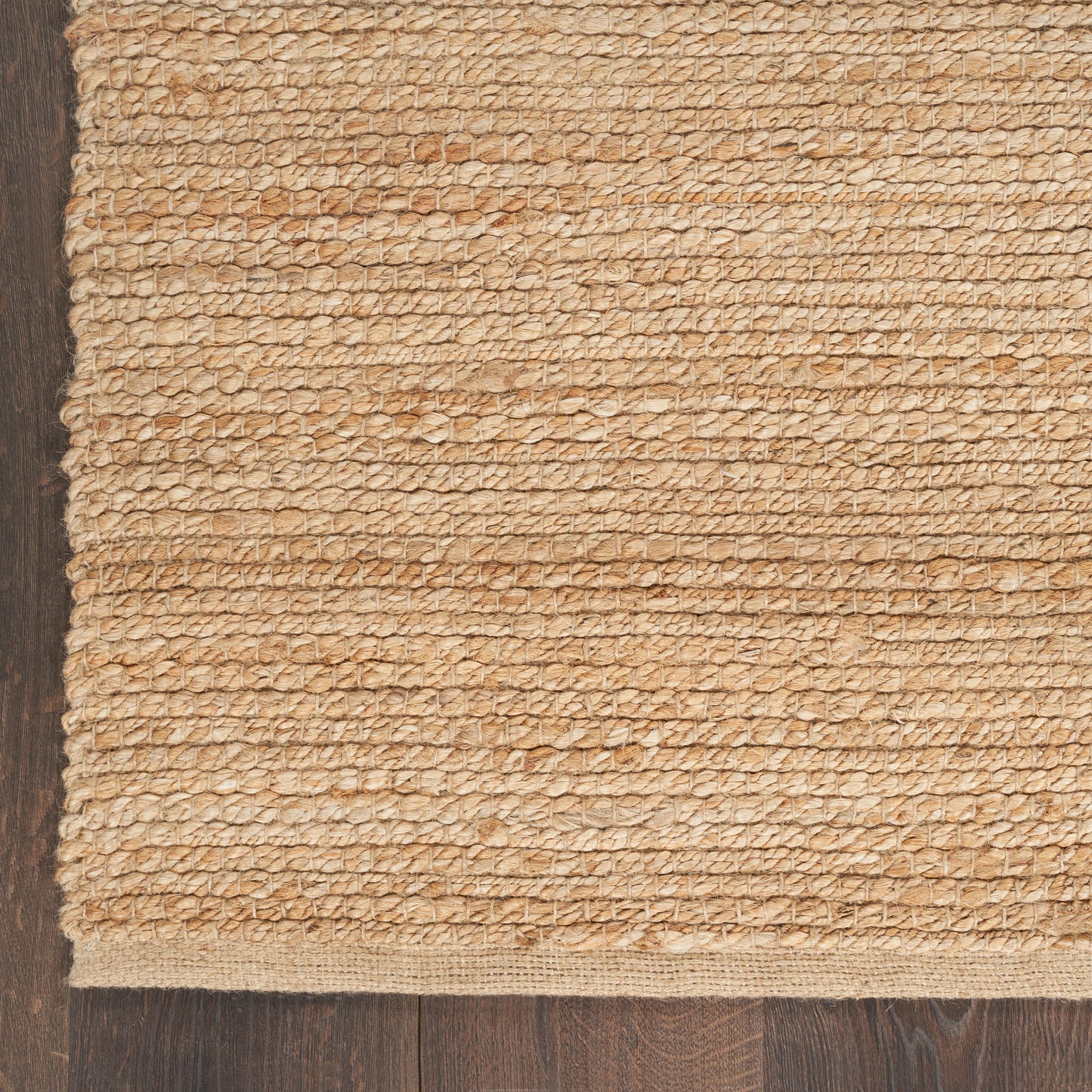 Natural beige jute rug with chunky looped texture on dark wood floor.