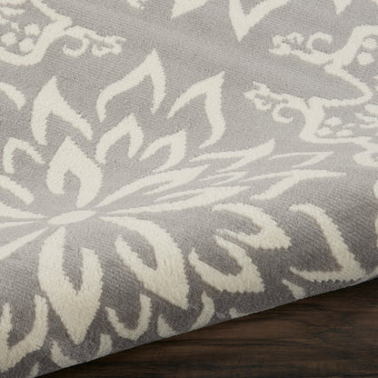 Grey fabric with white damask floral pattern, soft woven textile draped over dark wood surface.