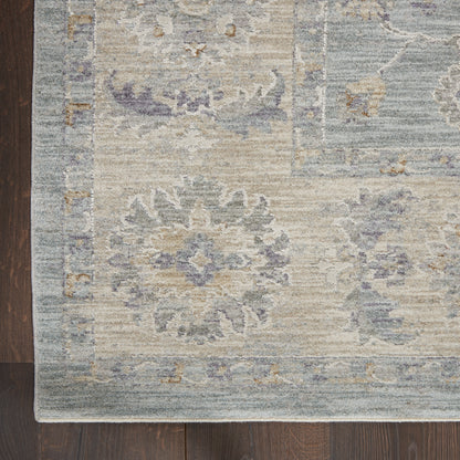 Distressed vintage-style area rug in soft blues and beiges with floral medallions on a dark wood floor.