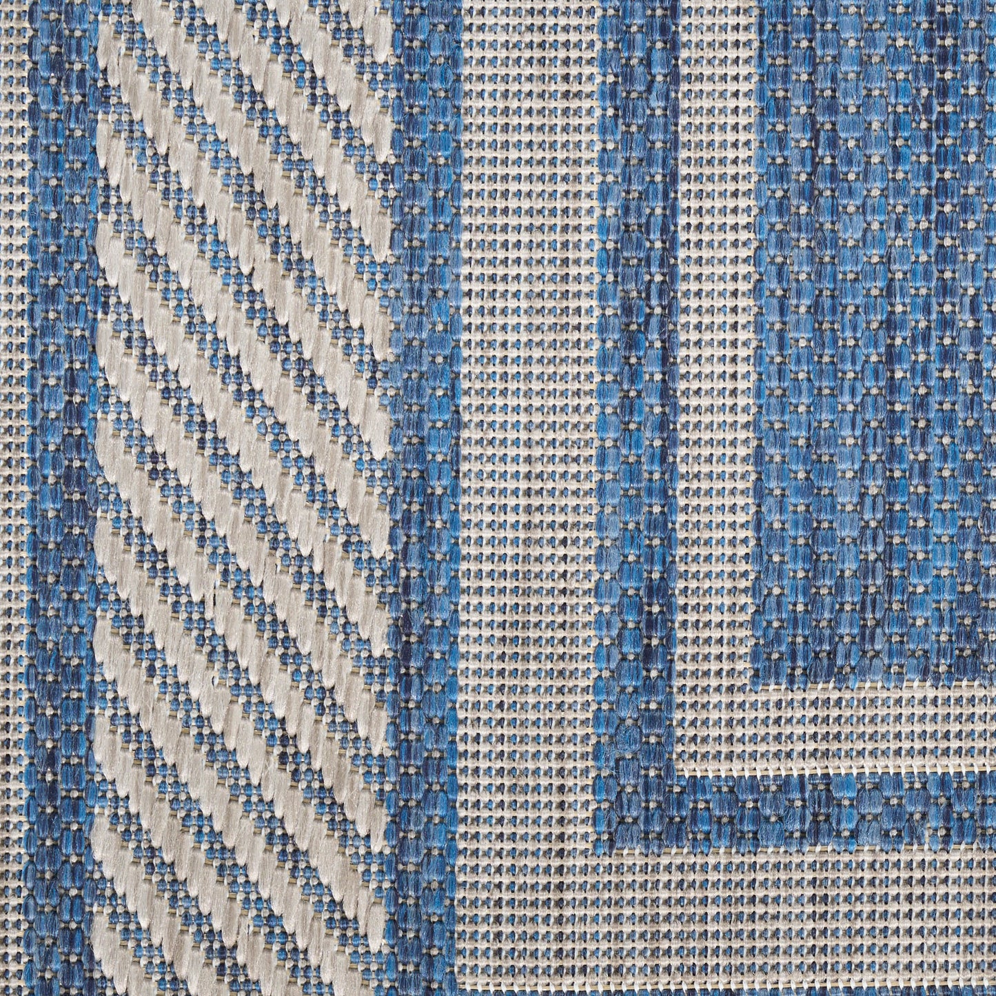 Blue and cream woven rug with a diagonal chevron on the left and a geometric stripe border; sturdy cotton.