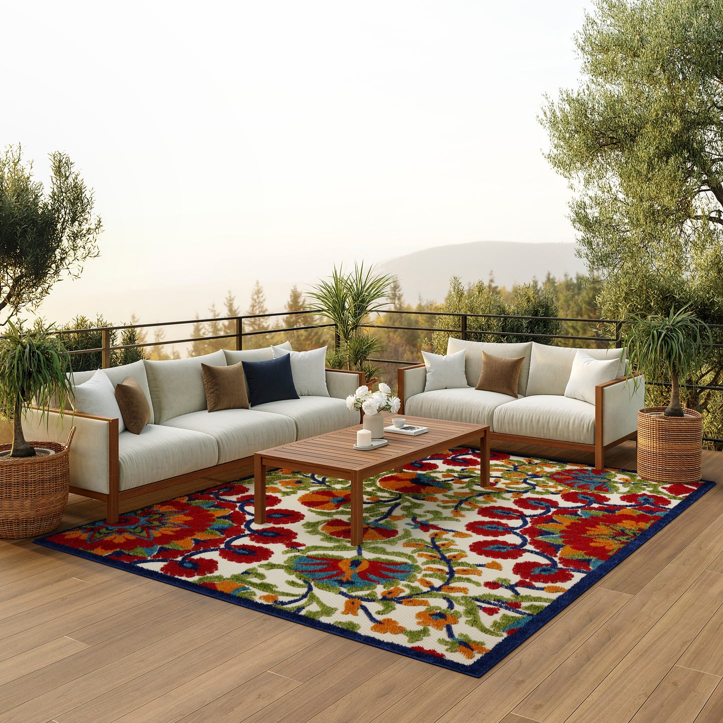 Outdoor sectional sofa with beige cushions on a vibrant floral rug; wooden coffee table, potted plants, and balcony view.