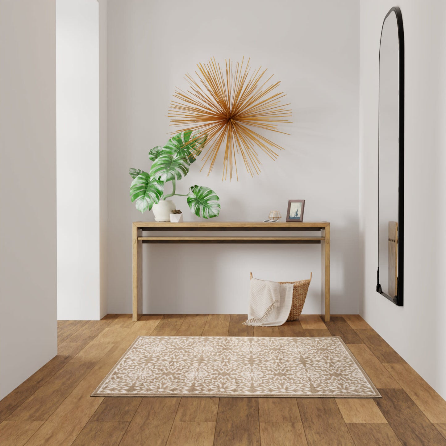 Natural wood console table with starburst wall art, monstera plant, basket, photo frame, beige rug and black curved mirror.