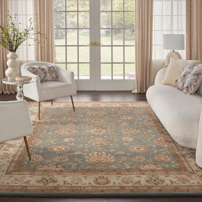 Living room with an ornate blue and beige floral area rug, cream sofa and chairs, glass French doors, and soft neutral decor.