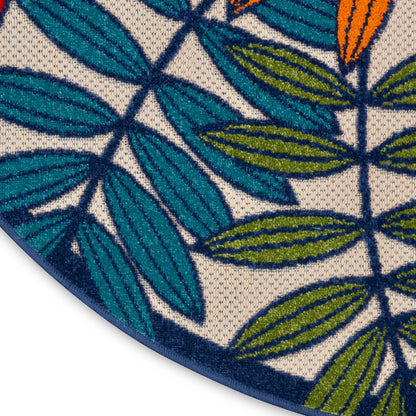Circular woven rug with teal and navy tropical leaf pattern on white background