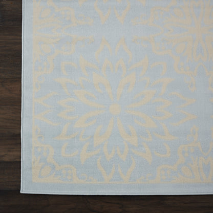 Light blue rug with ivory mandala motif & border, on dark wood floor.