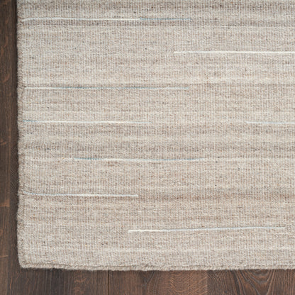 Natural beige woven rug with subtle blue flecks on dark wood floor; rectangular, textured jute-cotton blend.