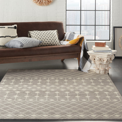Brown sofa with patterned cushions, light gray geometric rug, white carved side table with books in bright living room