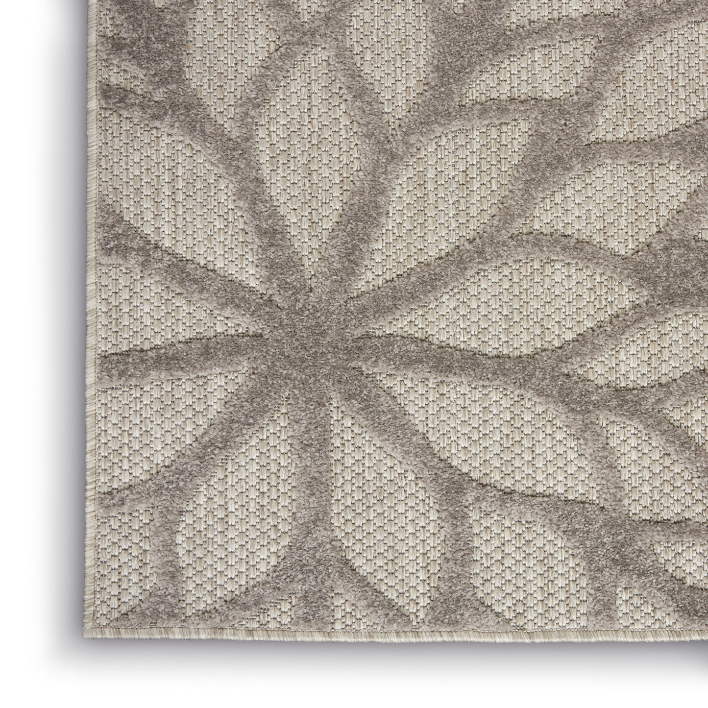 Beige rug with taupe raised palm-leaf pattern; woven textured background, neutral living-room decor.