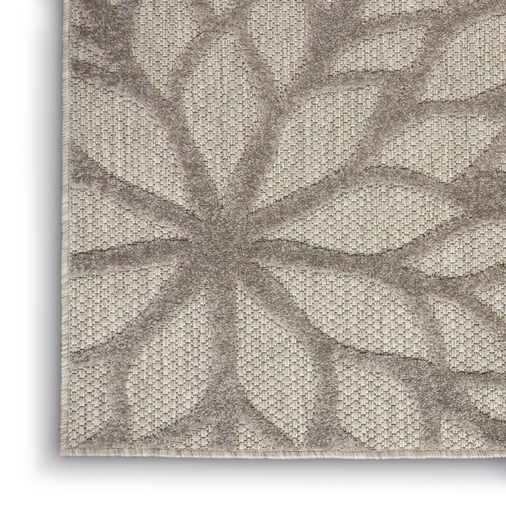 Beige rug with taupe raised palm-leaf pattern; woven textured background, neutral living-room decor.
