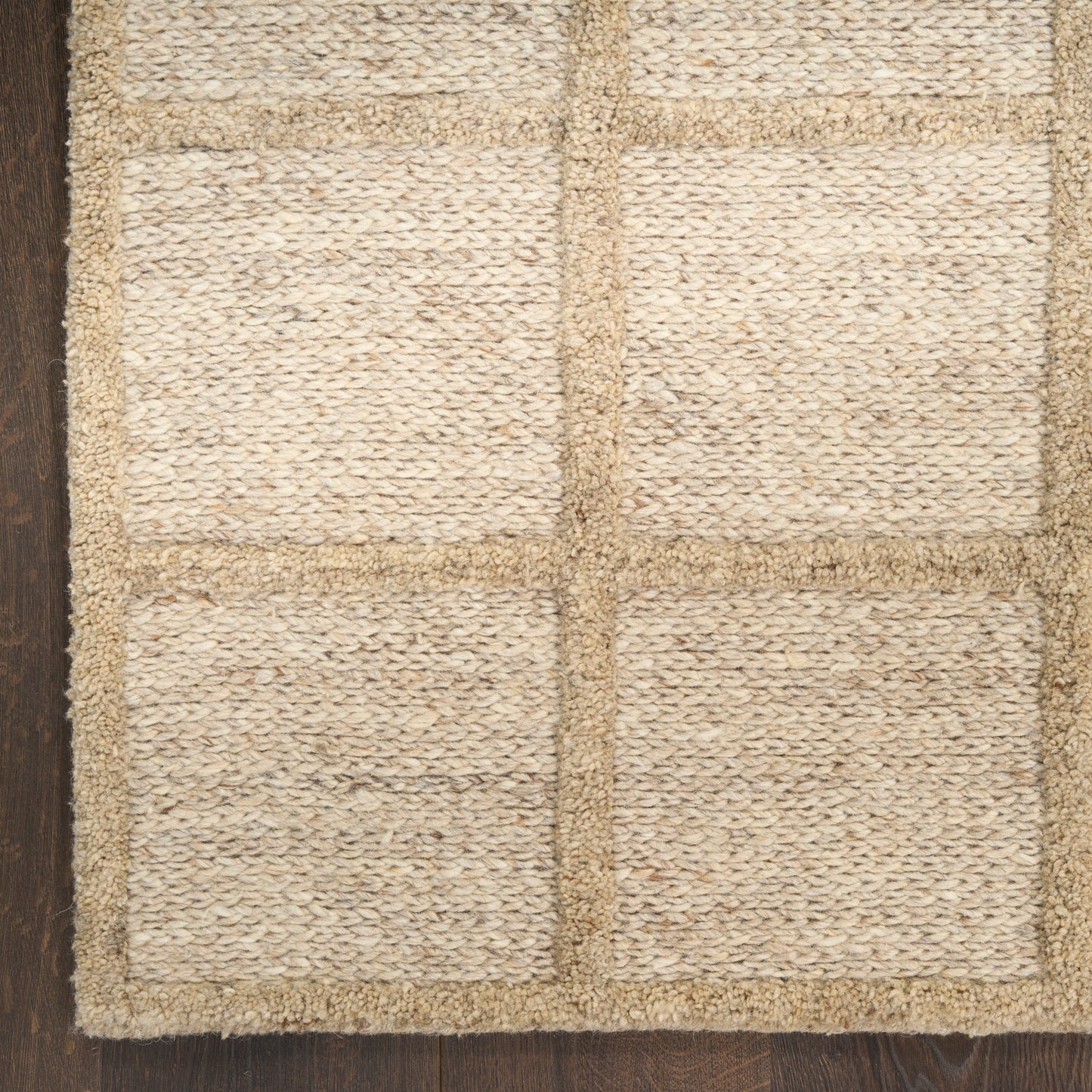Natural jute rug with beige square grid panels and rustic woven texture on dark wood floor.