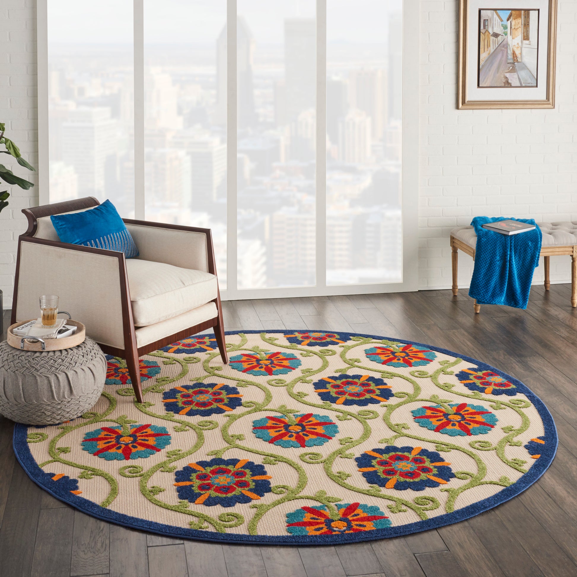 Round rug with blue border and colorful floral pattern in a modern living room with cream armchair and blue cushions.