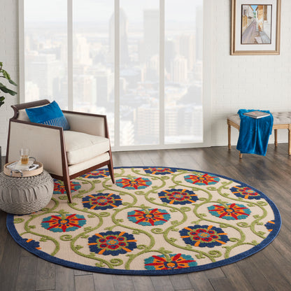 Round rug with blue border and colorful floral pattern in a modern living room with cream armchair and blue cushions.
