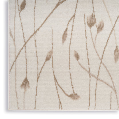 Beige textured rug with light brown botanical vine pattern and leaf accents; woven surface and visible edge.