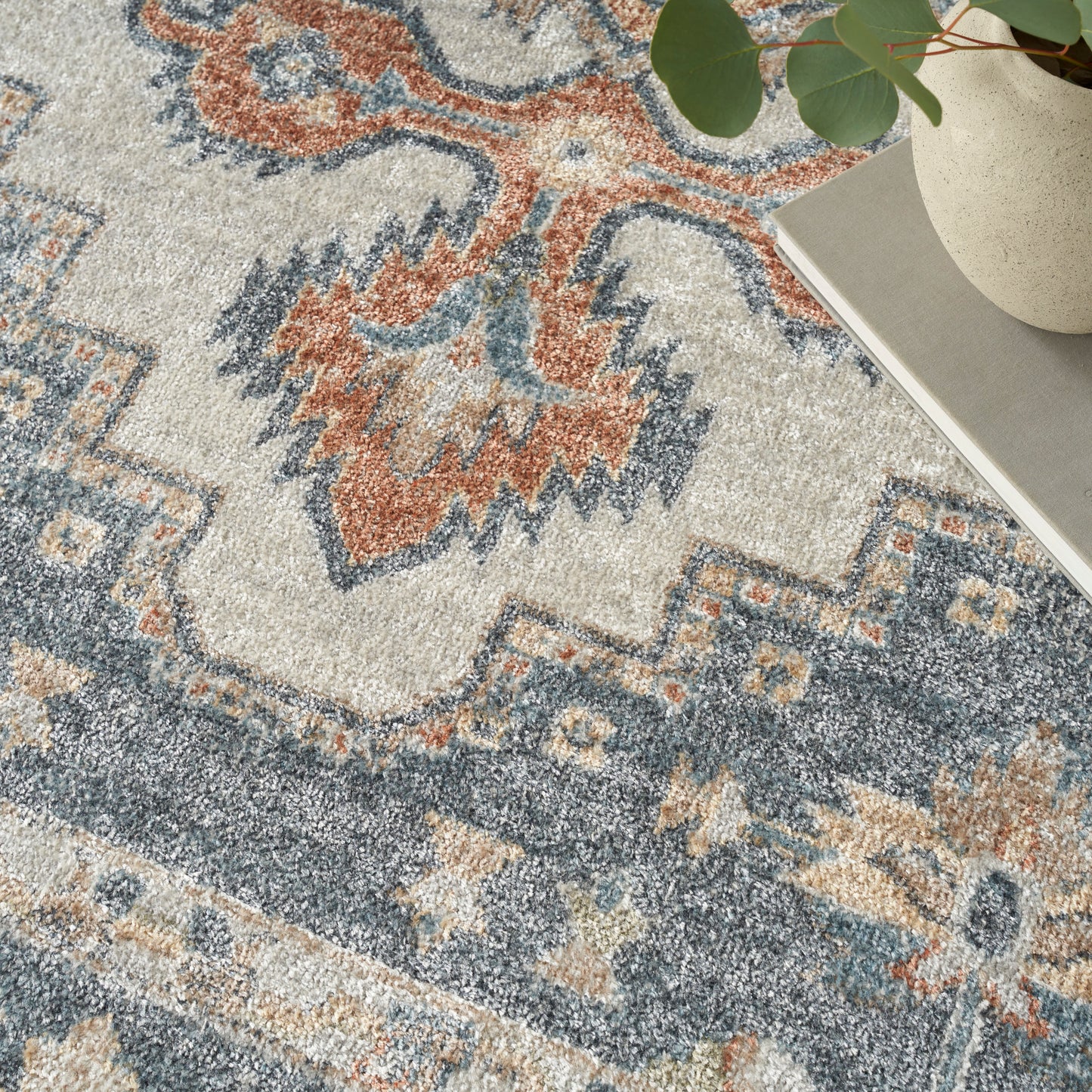 Rectangular vintage-style area rug with ivory, blue and rust geometric motifs; soft textured pile for living spaces.