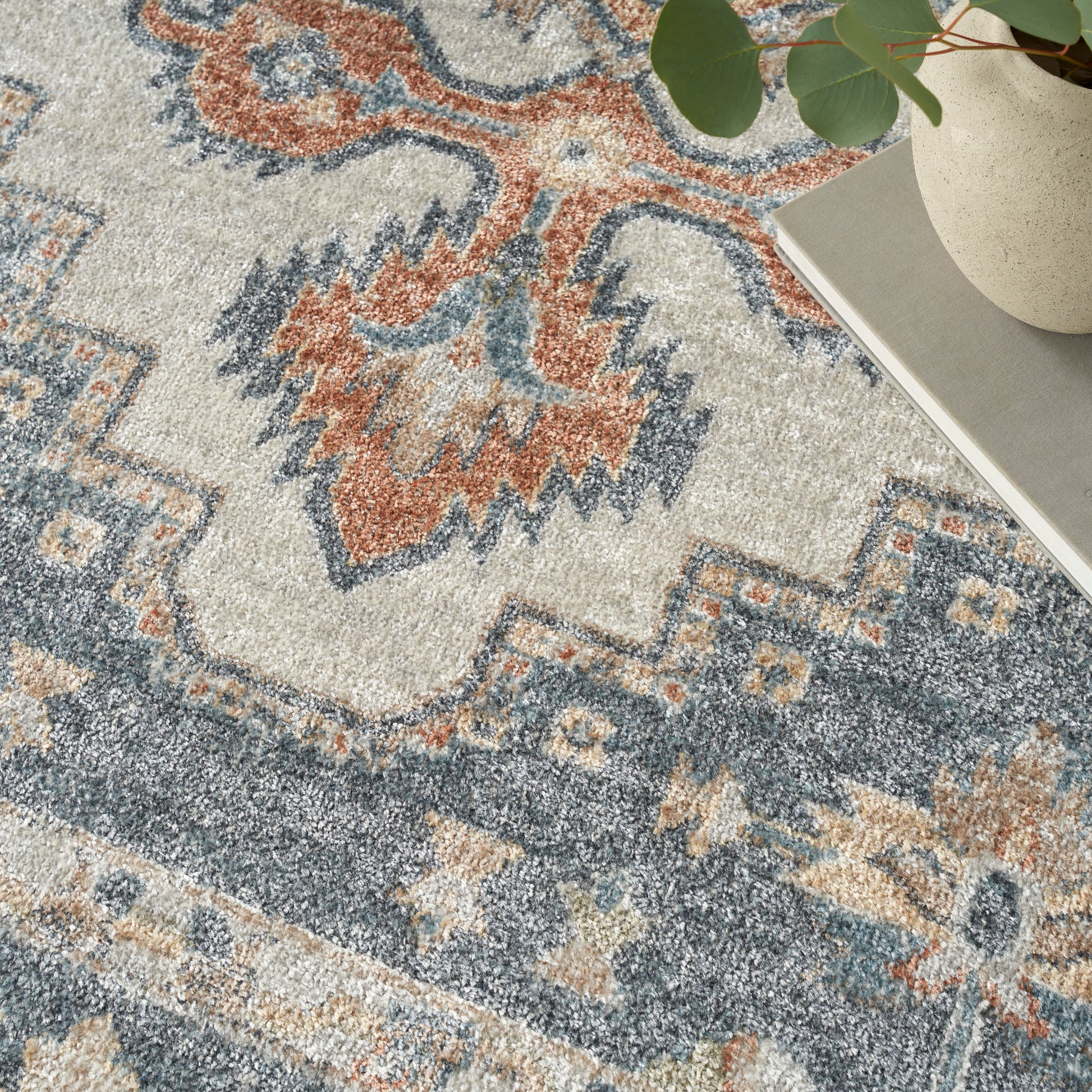 Rectangular vintage-style area rug with ivory, blue and rust geometric motifs; soft textured pile for living spaces.