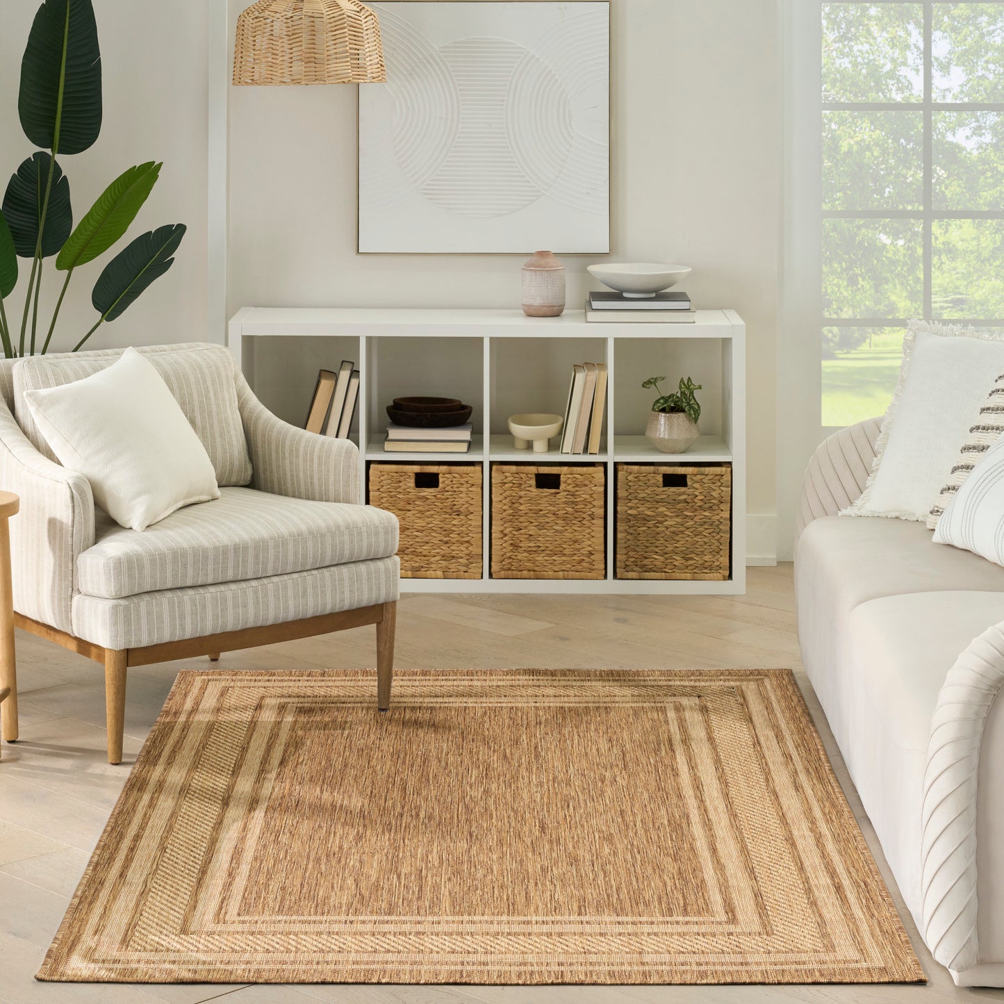 Neutral living room with white cubby storage, woven baskets, beige braided rug, striped armchair, white sofa, plant and wicker pendant light