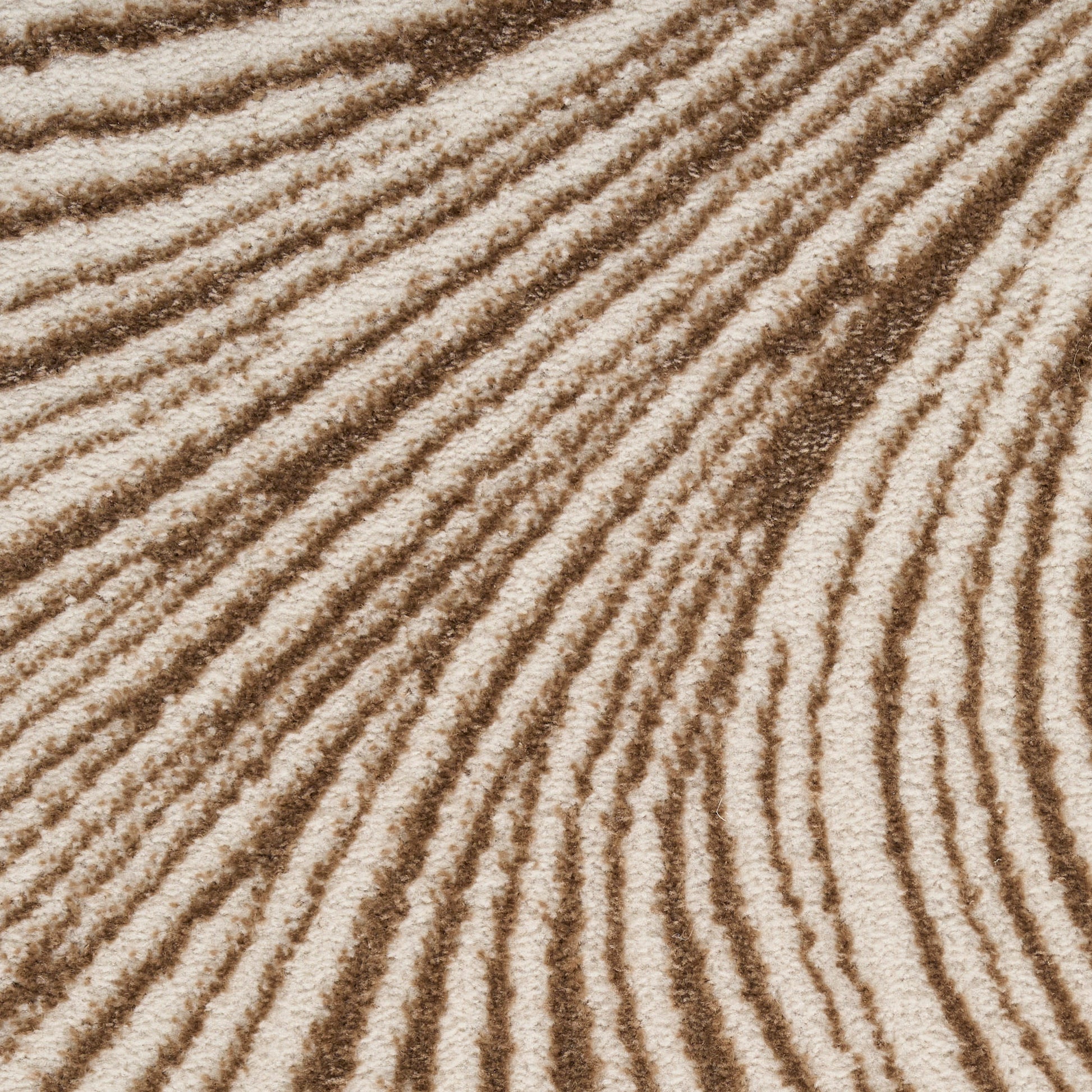 Close-up of beige-brown rug texture with a sand-textured surface and repeating wavy ridges.