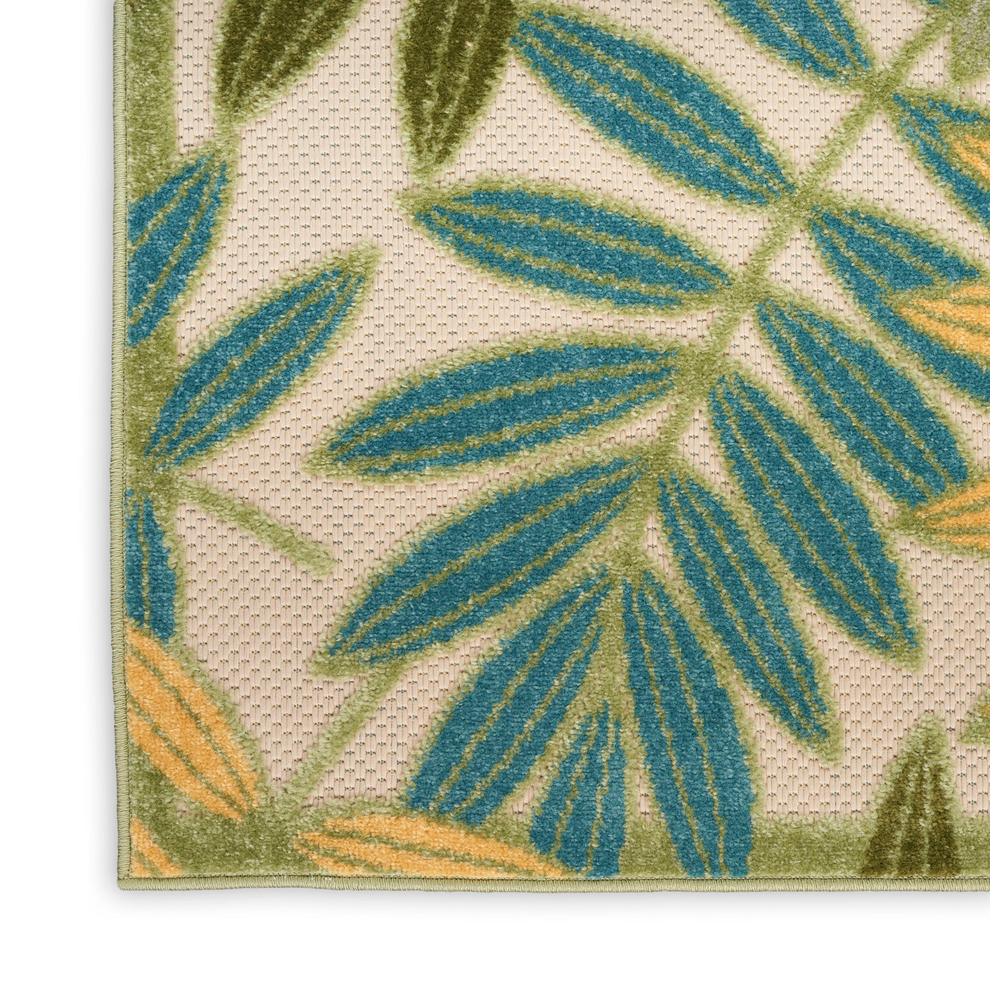 Beige tufted rug with blue-green leaf pattern and orange accents, bound edge, close-up corner view.