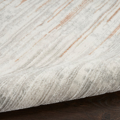 Close-up of a light gray and cream marbled rug with subtle orange streaks on dark wood floor.