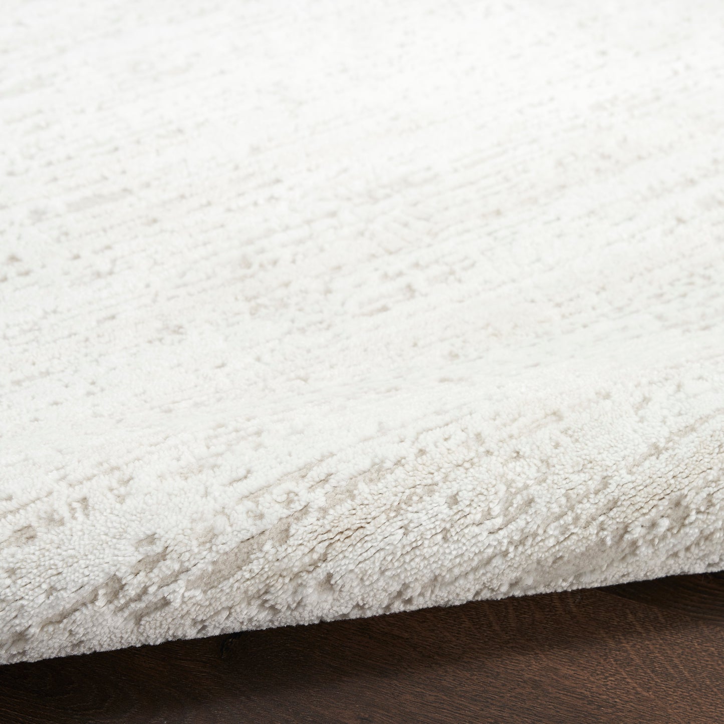 Cream plush rug with subtle textured pattern and soft pile on dark wood floor.