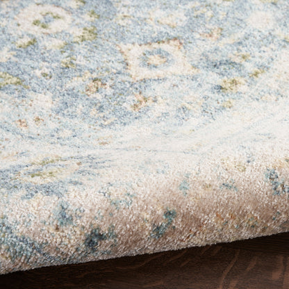 Soft blue and ivory abstract floral area rug with muted beige accents and a rolled edge on wood floor.