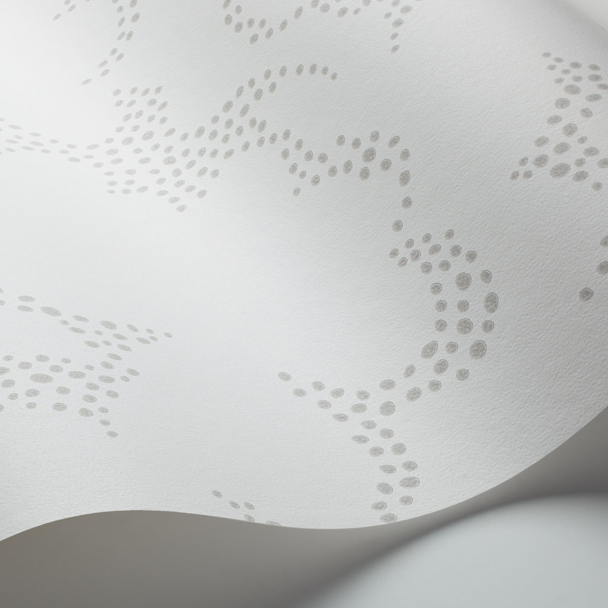 White textured material with delicate gray dotted lace pattern and a curved fold.