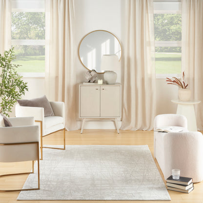 Bright neutral living room with cream seating, light wood cabinet, round mirror, beige curtains, rug, and potted greenery.