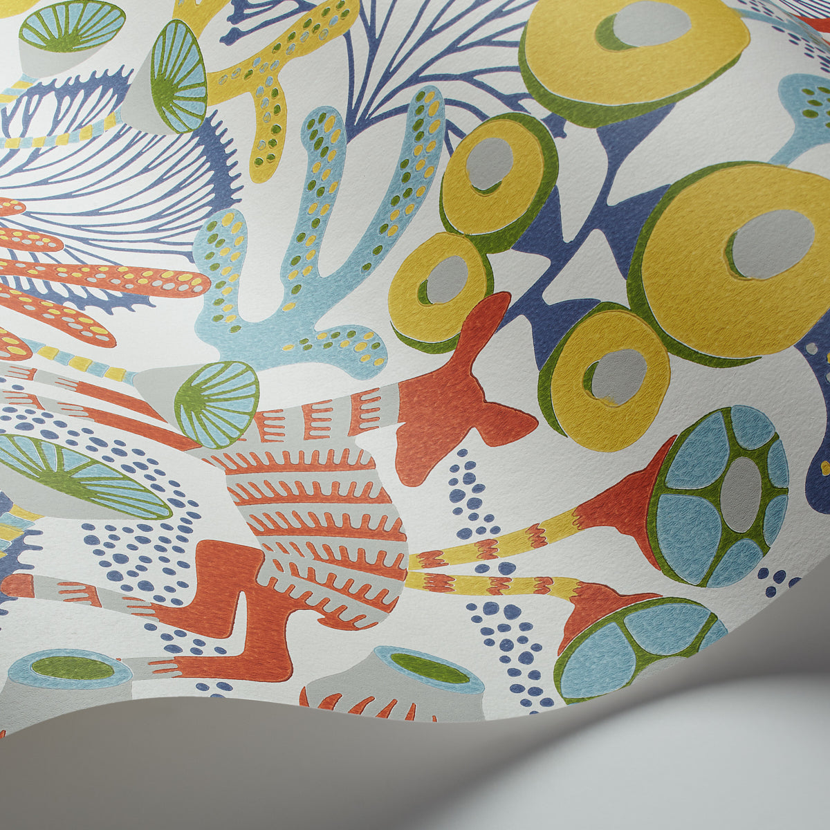 Bright abstract coral reef print with yellow, green and blue rings and coral shapes on white background.