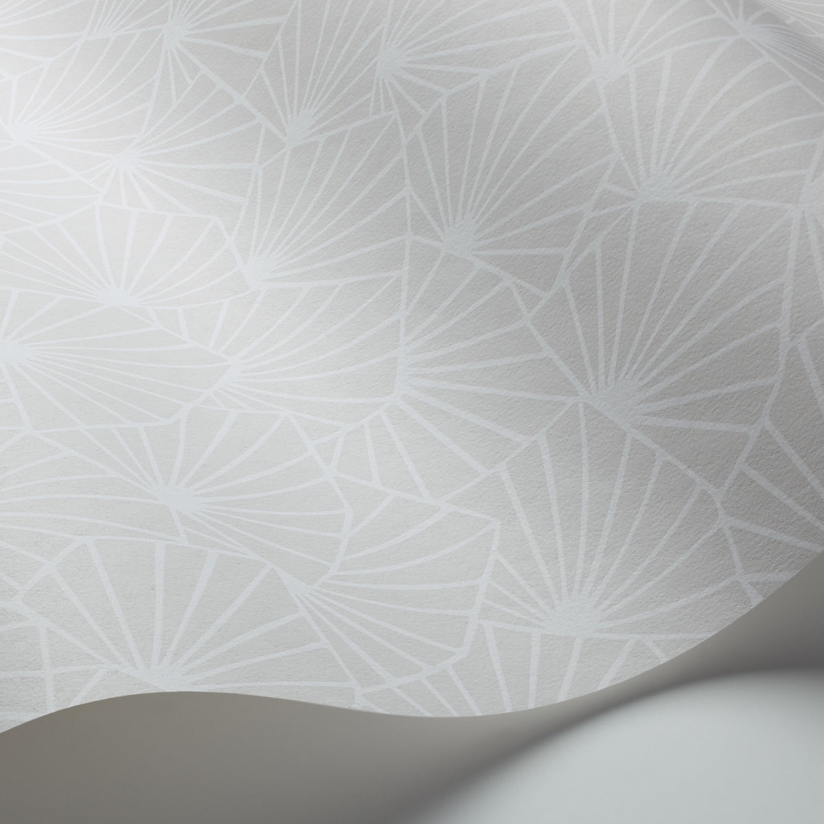 Pale gray wallpaper with a repeating white geometric fan pattern and a curved rolled edge.