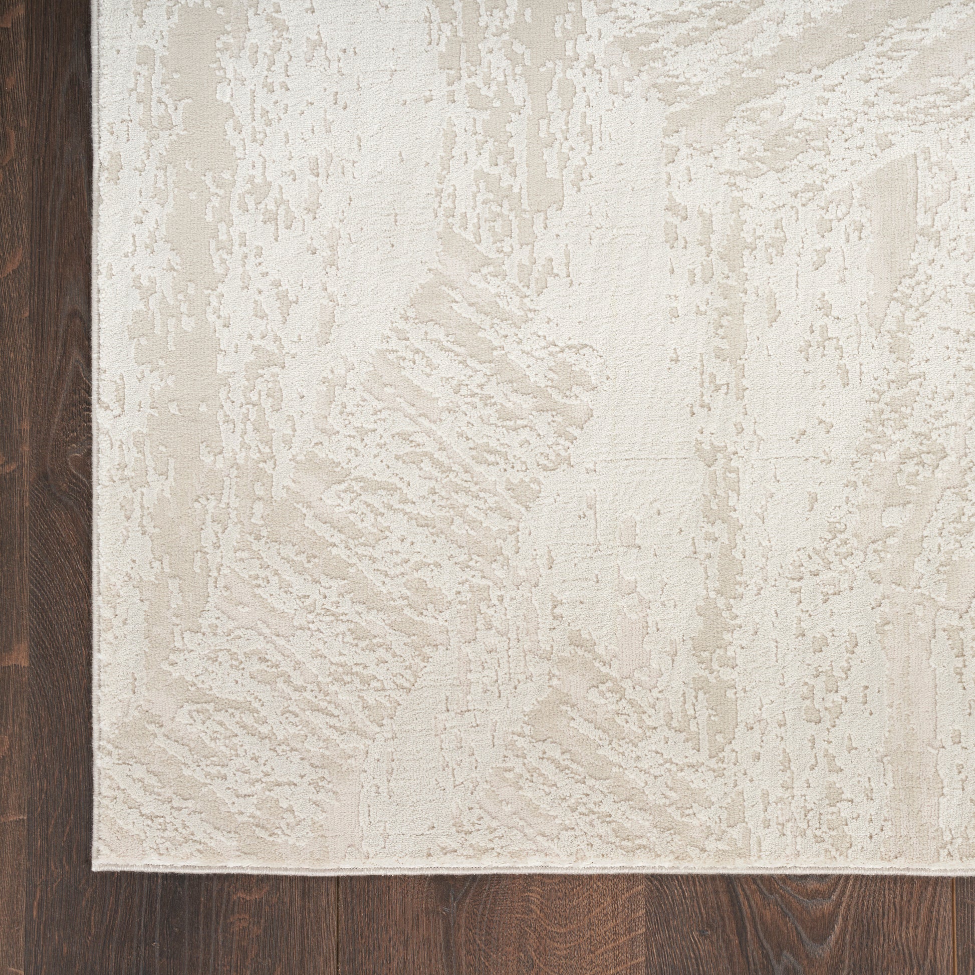 Cream textured area rug with subtle abstract pattern on dark hardwood floor.