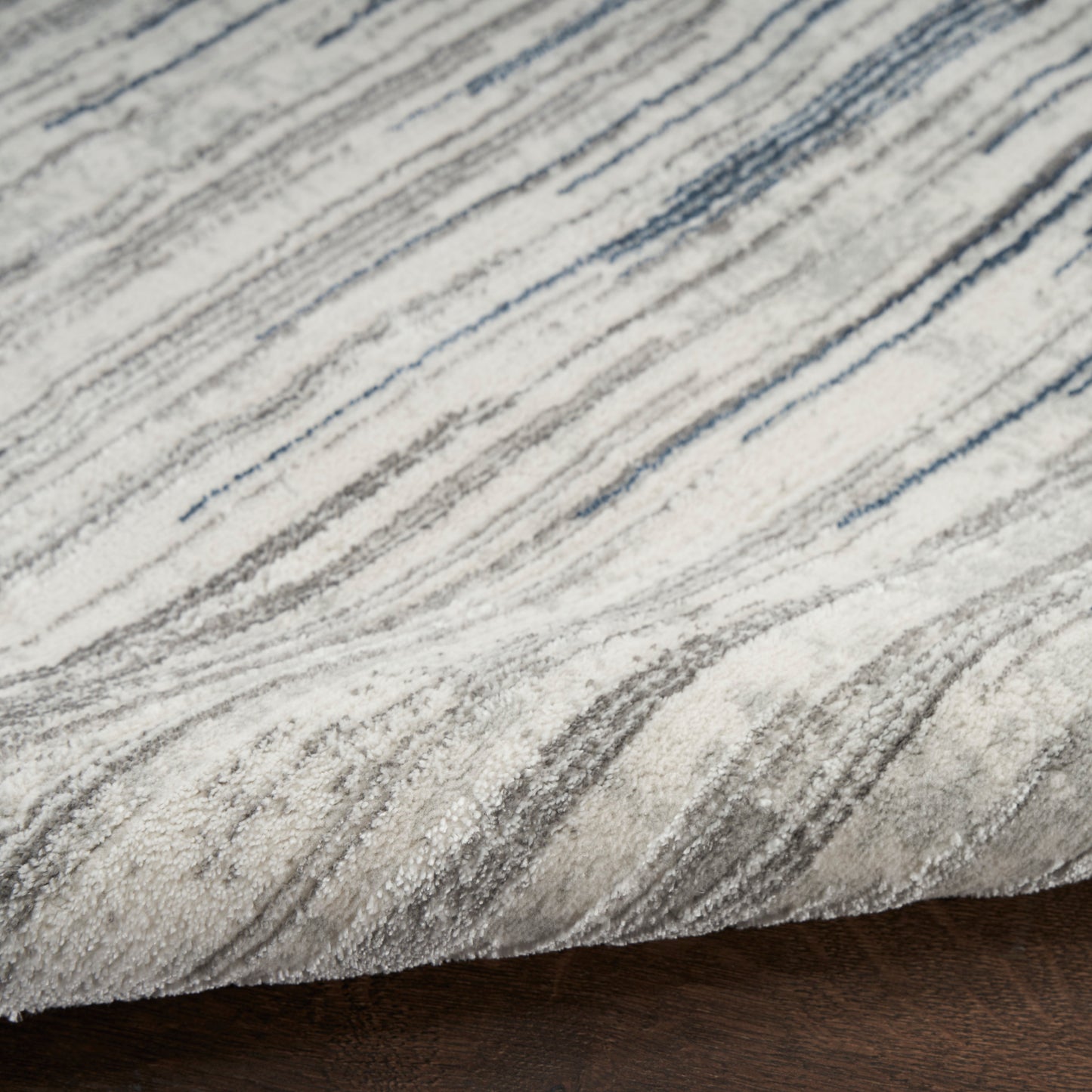 Gray and ivory striped area rug with a soft, textured pile on dark wood floor.
