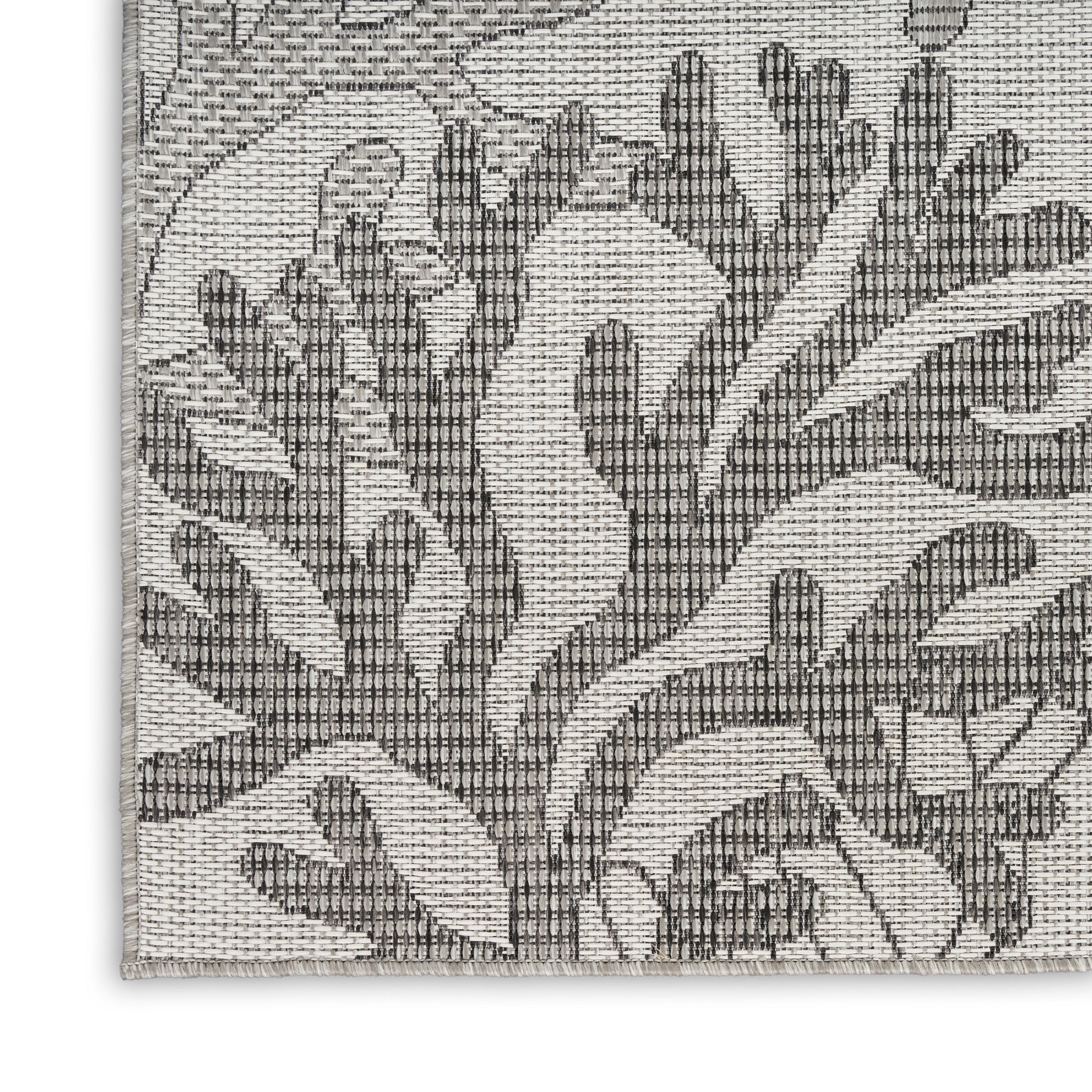 Woven rug corner featuring gray damask botanical pattern on a cream background with a textured jacquard weave, 5' x 7'.