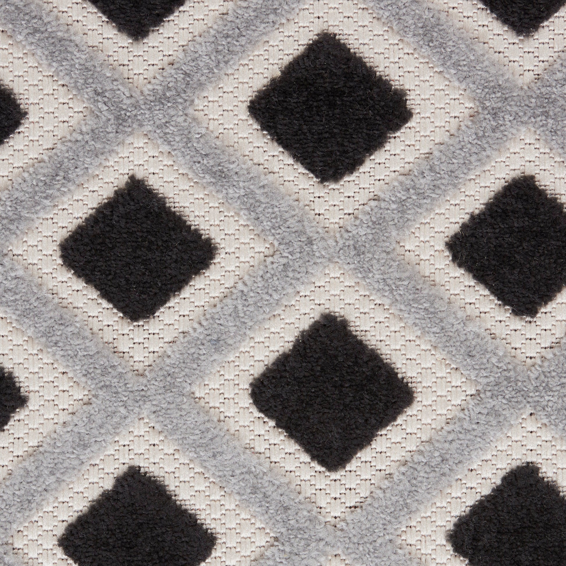 Geometric diamond-pattern rug with charcoal diamonds on a cream-gray background; woven, soft texture.