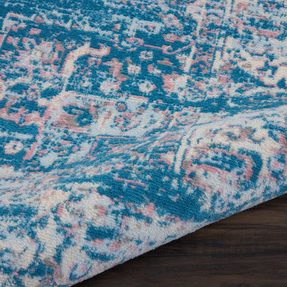 Blue and cream rug with pink highlights in a vintage Persian-inspired pattern, plush pile on wood floor.
