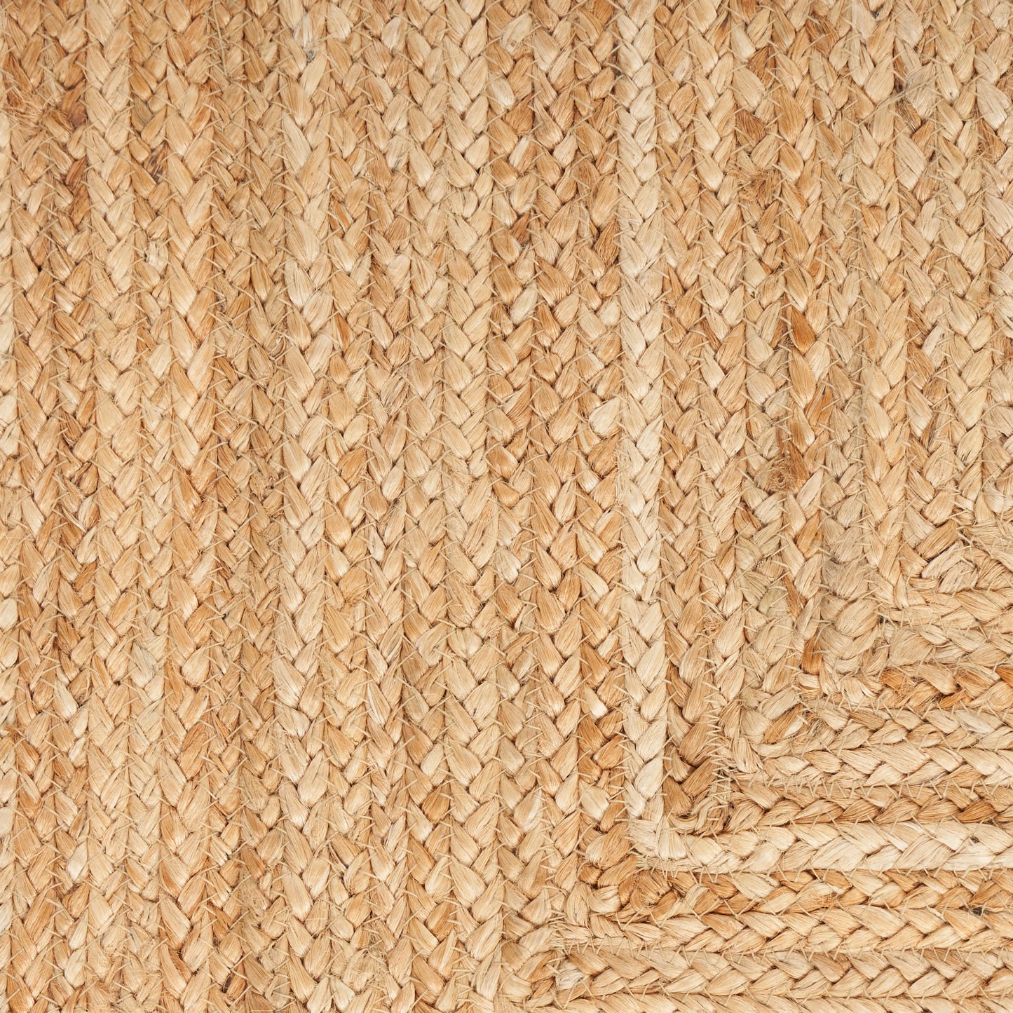 Natural jute braided rug close-up with woven pattern and corner border, rustic beige rug.