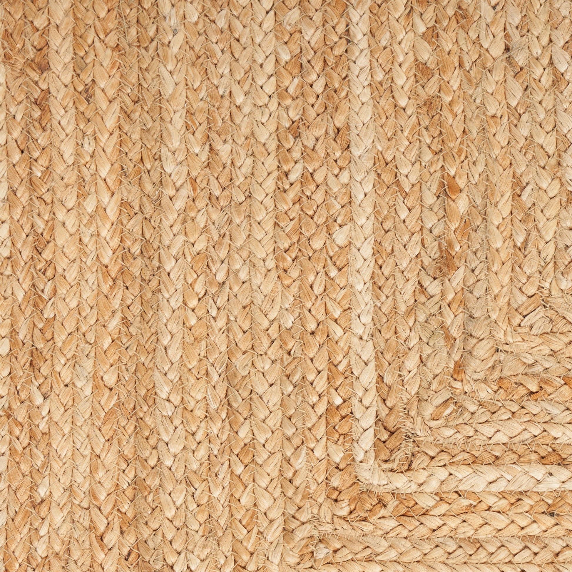 Natural jute braided rug close-up with woven pattern and corner border, rustic beige rug.