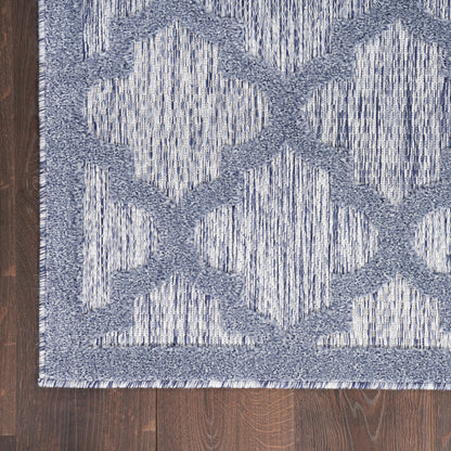 Blue and gray geometric rug with interlocking diamond lattice on dark wood floor, woven texture.