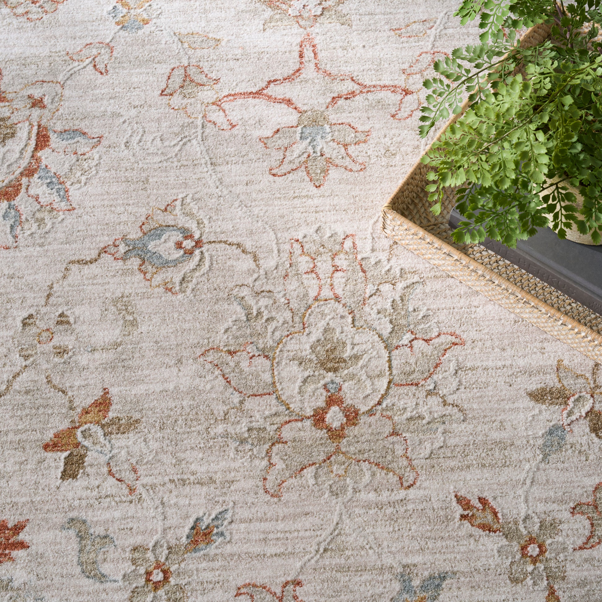 Beige floral area rug with vintage pink, blue & green blossoms; soft woven texture, with a wicker planter nearby.