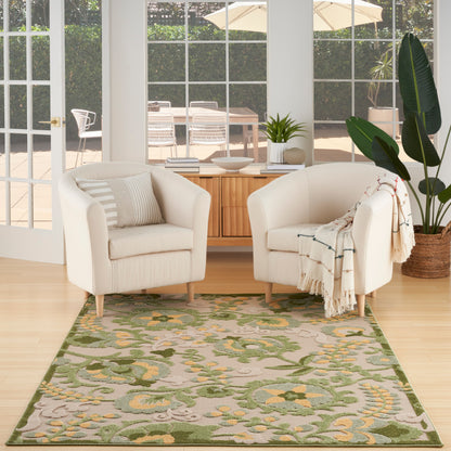 Pair of cream upholstered armchairs with light wood legs, on a green botanical rug in a bright living room with plants.