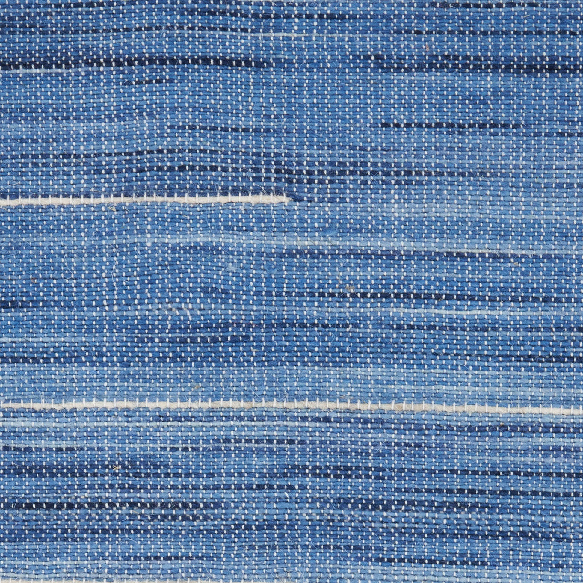 Close-up of blue denim-style woven rug with white streaks and a speckled texture.
