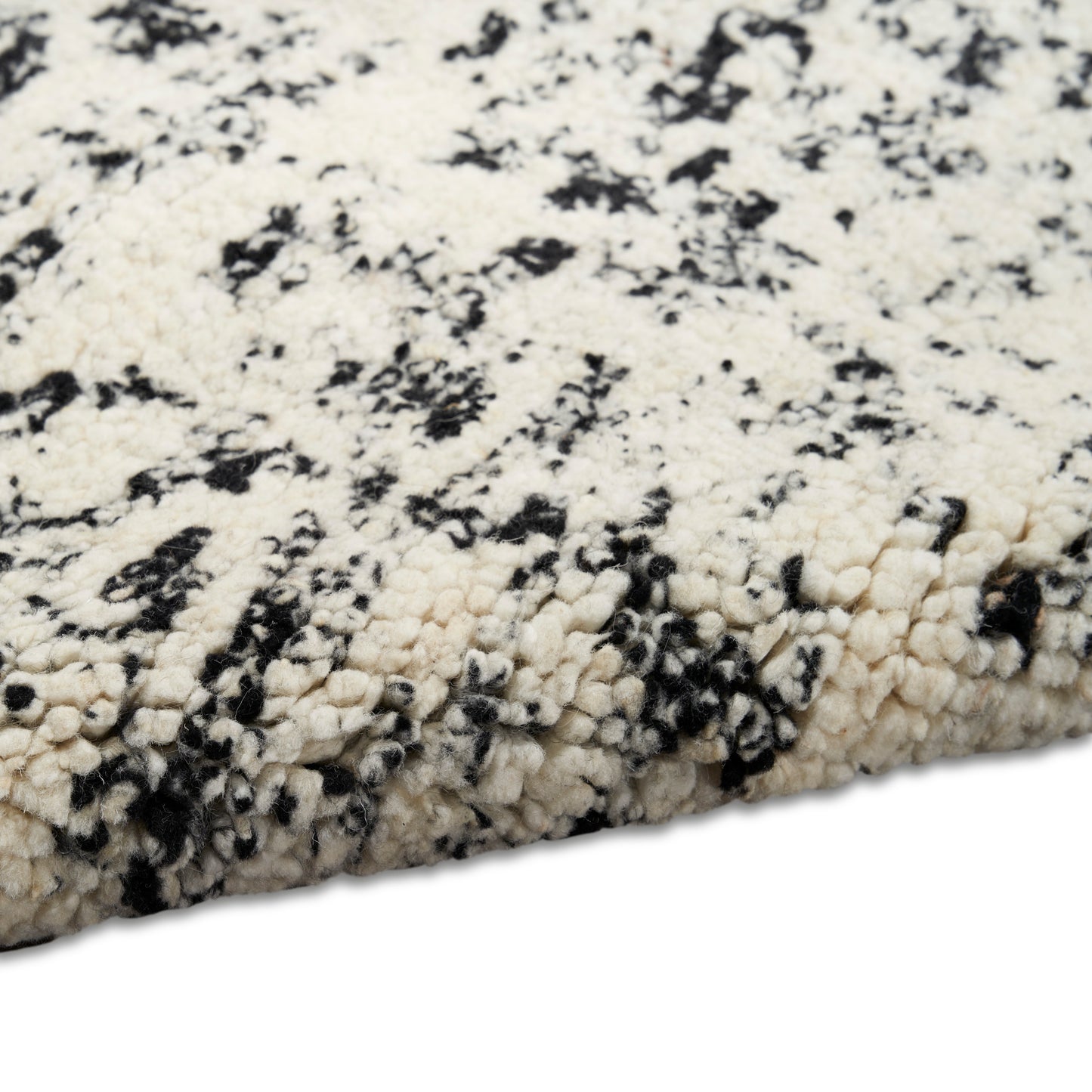 Cream and black speckled shag rug with chunky plush fibers, contemporary marbled pattern.