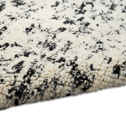 Cream and black speckled shag rug with chunky plush fibers, contemporary marbled pattern.