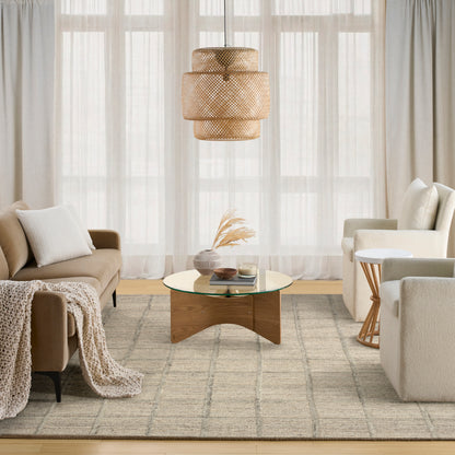 Neutral-toned 10' x 14' modern rug with a soft textured surface, seen in a living room with beige sofas, a woven pendant light, and a round glass coffee table.